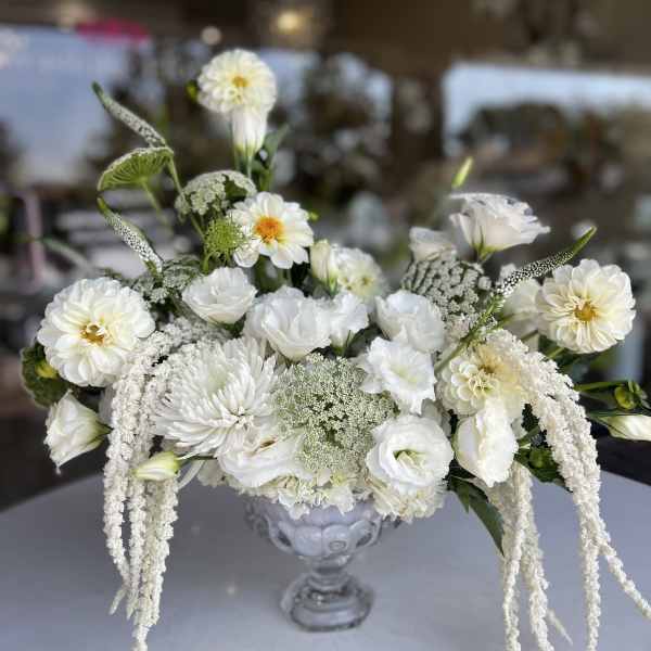 White floral arrangement in a clear glass vase with cascading blooms