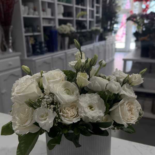 White roses and lisianthus arranged in a ribbed glass vase.