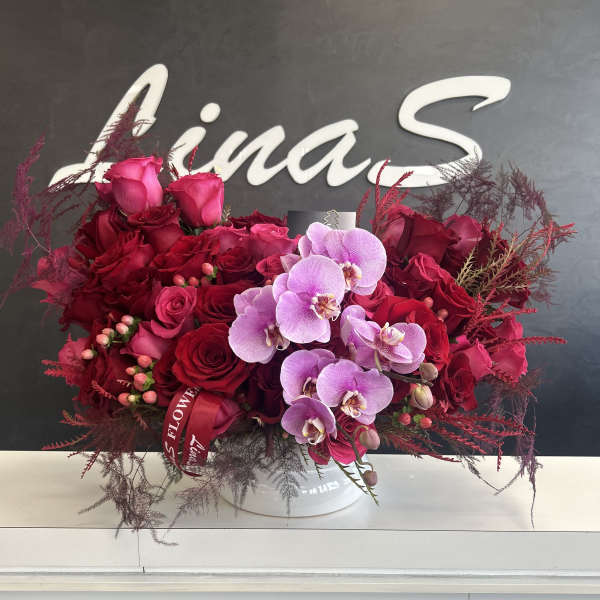 Red rose and pink orchid arrangement in a white vase