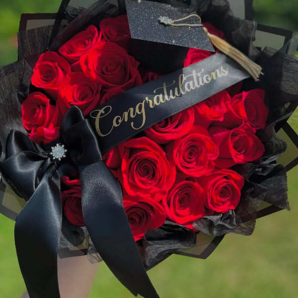 Bouquet of red roses wrapped in black paper with a congratulatory ribbon