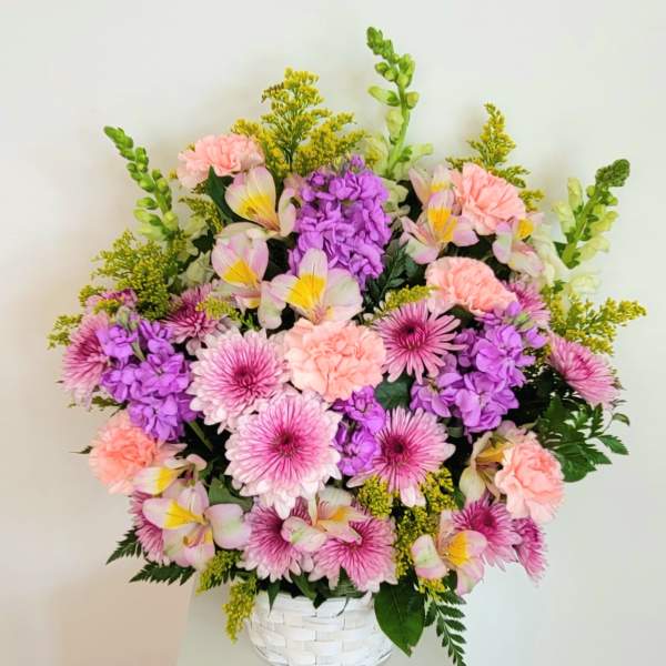Pink and purple mixed flowers arranged in a white basket vase