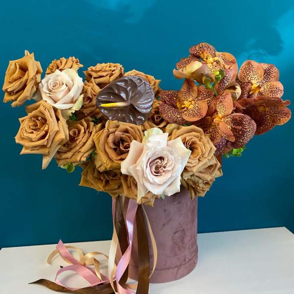 Bouquet of tan roses and spotted orchids in a velvet hatbox