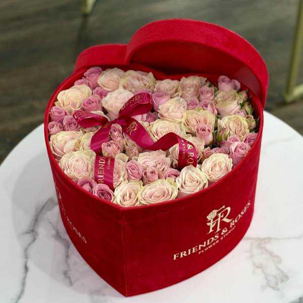 Heart-shaped red box filled with pink and cream roses