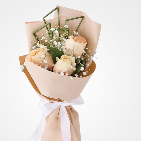 Peach roses wrapped in blush paper with a white ribbon
