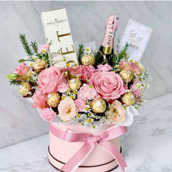 Pink rose bouquet with chocolates and champagne in a round gift box
