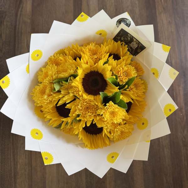 Bouquet of yellow sunflowers and mums wrapped in white paper