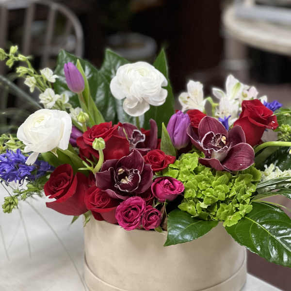Mixed bouquet of red and white roses with orchids in a beige box