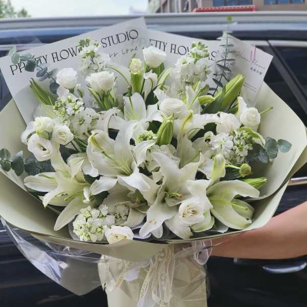 White lily and rose bouquet wrapped in cream paper
