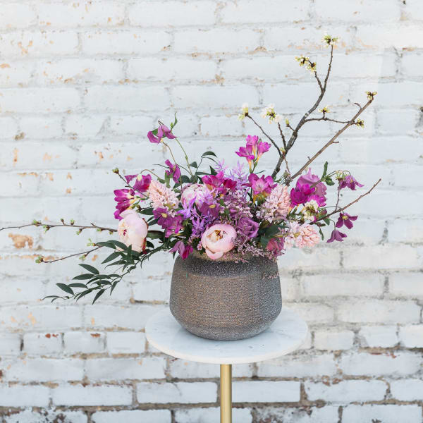 Pink and purple floral arrangement in a textured vase