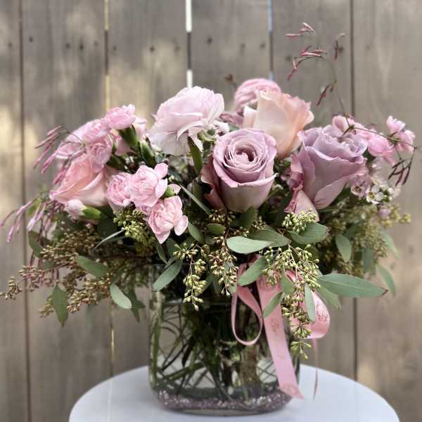 Pink rose bouquet in a clear glass vase with ribbon