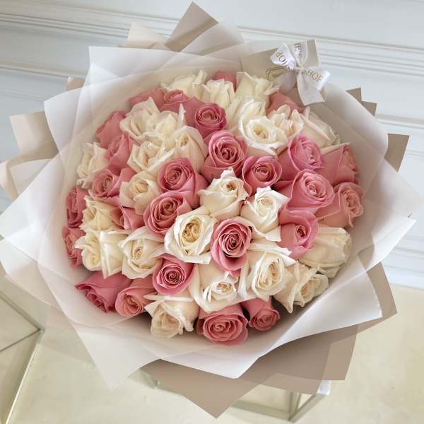 Bouquet of pink and white roses wrapped in layered paper