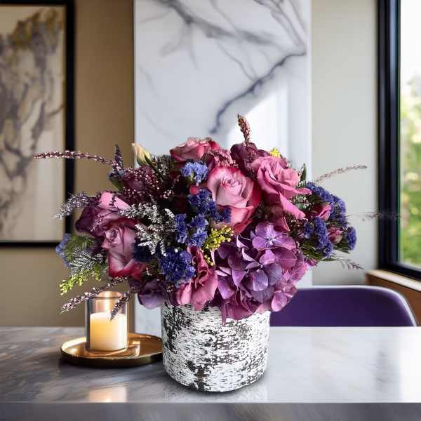 Pink and purple floral arrangement in a white textured vase