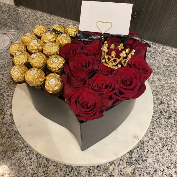 Heart-shaped box of red roses and gold-wrapped chocolates with a card.