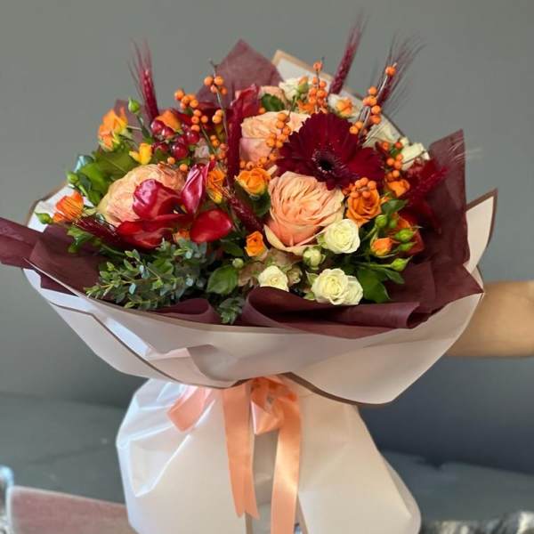 Bouquet of peach, red, and white roses with orange berries