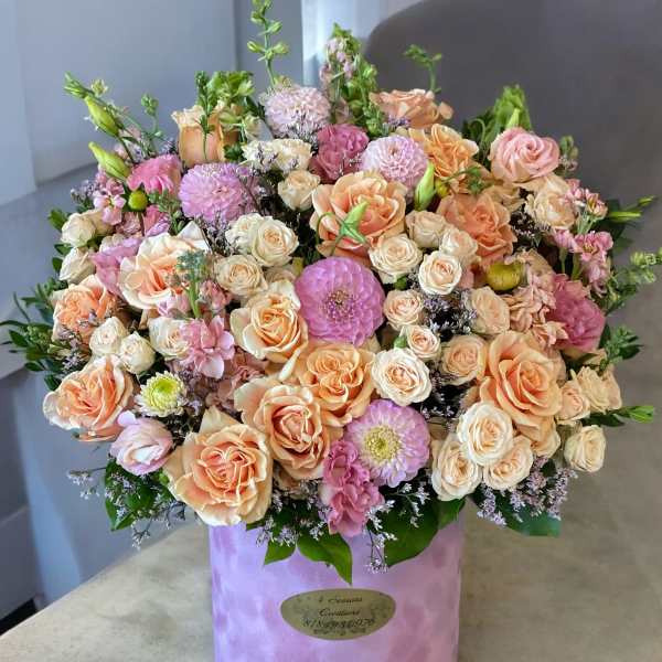 Large pastel bouquet of roses and pink blooms in a lavender hat box