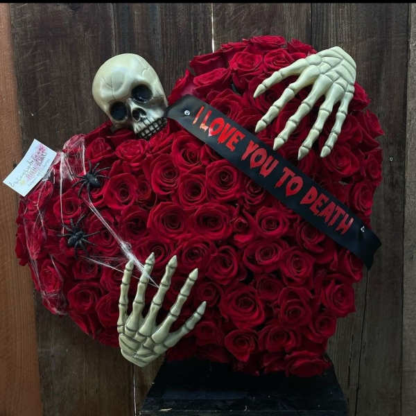 Heart-shaped red rose arrangement with skeleton hands, skull, and a "I LOVE YOU TO DEATH" ribbon