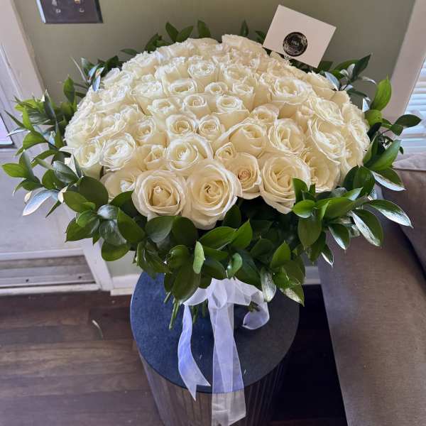 Large bouquet of white roses with a green leaf border and white ribbon