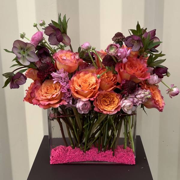 Mixed pink and orange flower arrangement in a clear rectangular vase