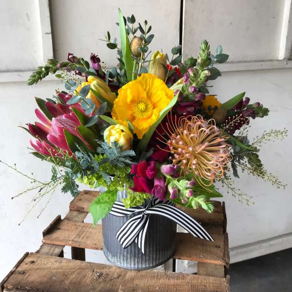 Colorful mixed bouquet in a striped ribbon-tied metal container