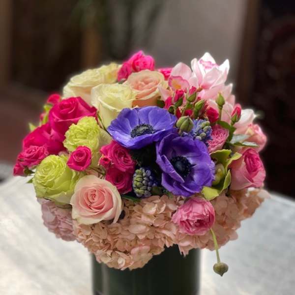 Colorful bouquet of roses, anemones, and hydrangeas in a glass vase