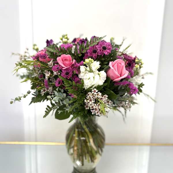 Pink roses and purple daisies in a glass vase