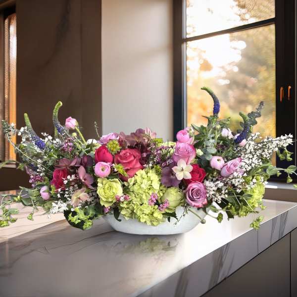 Low floral centerpiece with pink and green blooms in a white bowl.