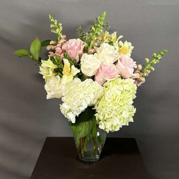 Pink and white roses with hydrangeas in a glass vase