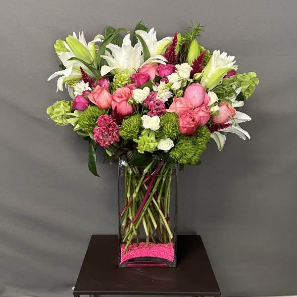 Mixed bouquet of pink and white flowers in a tall glass vase