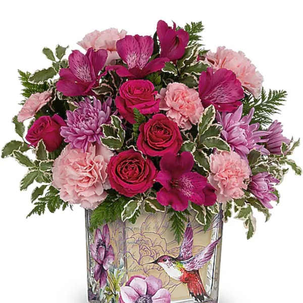 Pink and purple bouquet in a square glass vase with bird artwork