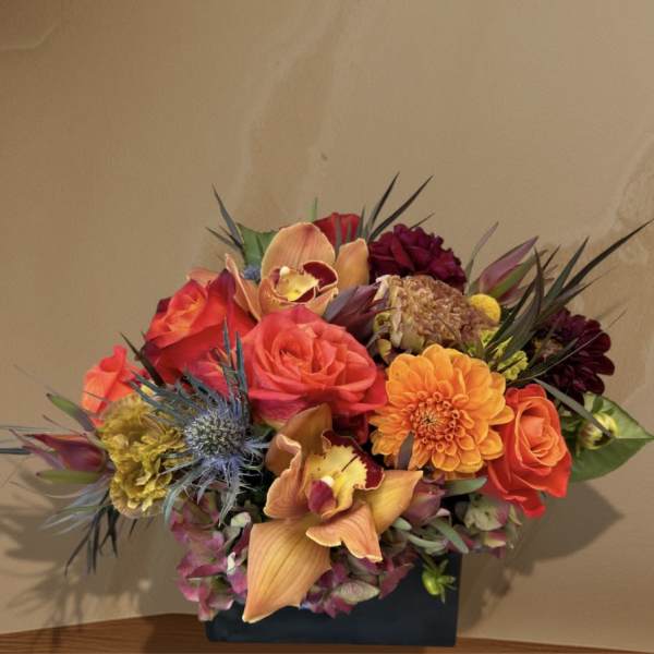 Colorful bouquet with roses, orchids, and dahlias in a dark vase