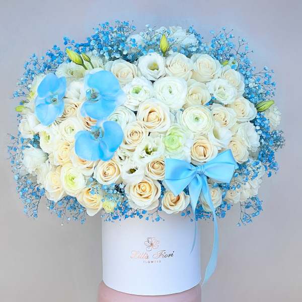 White rose bouquet with blue orchids and a blue ribbon in a white box