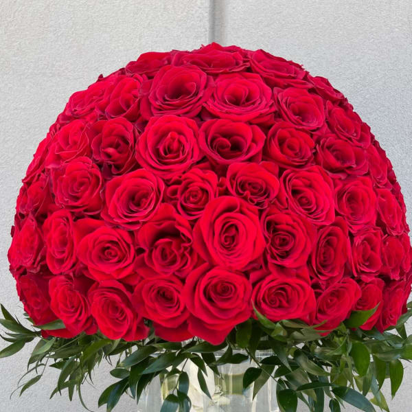 Large dome of red roses in a clear glass vase with white orchids inside
