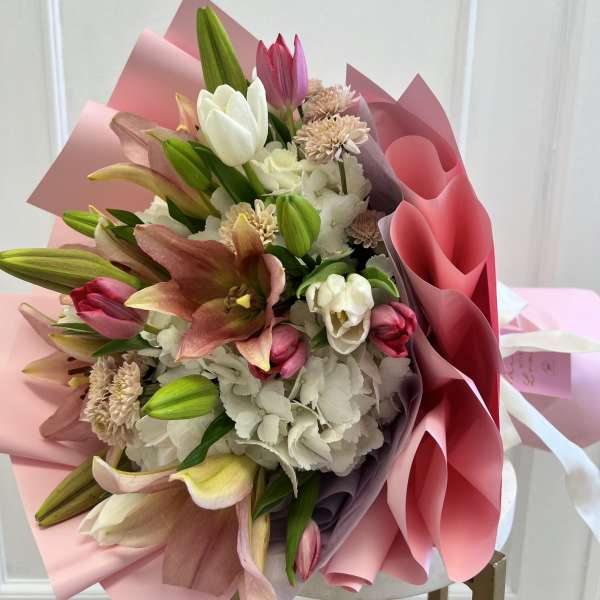 Pink and white bouquet with lilies and tulips wrapped in pink paper
