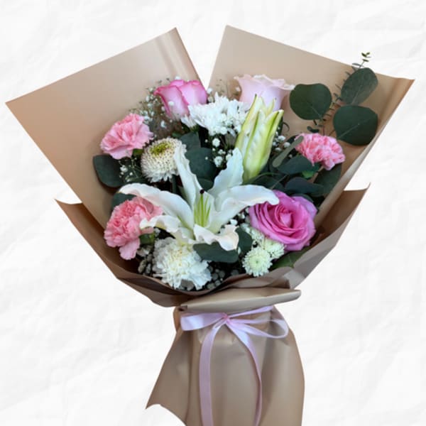 Bouquet of pink and white flowers wrapped in brown paper with a ribbon