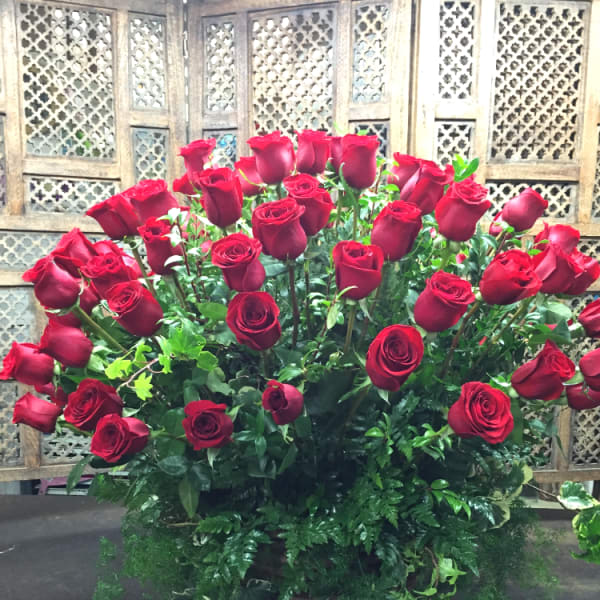 Large bouquet of red roses with greenery in a basket