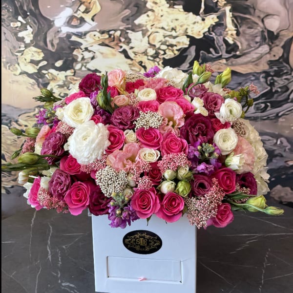 Pink, white, and purple roses arranged in a white box