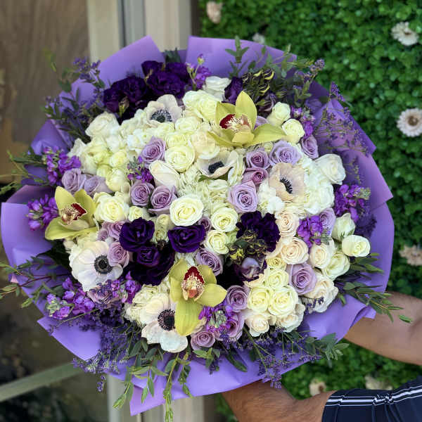 Bouquet of white, lavender, and deep purple flowers wrapped in purple paper