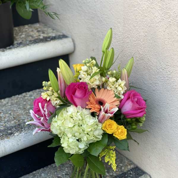 Mixed bouquet of pink roses, lilies, and hydrangea in a glass vase