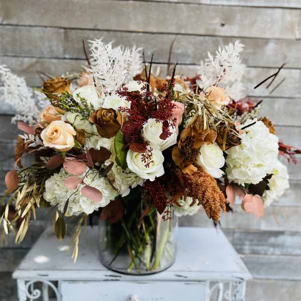 Mixed bouquet of white, peach, and brown roses in a glass vase