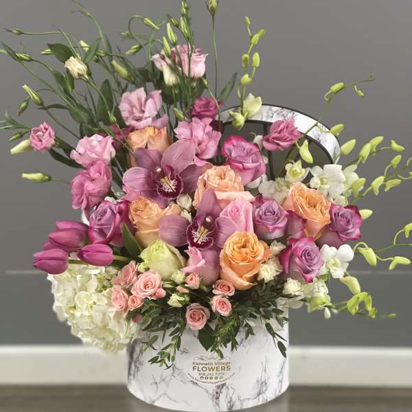 Mixed pink and peach floral arrangement in a marble-print hat box