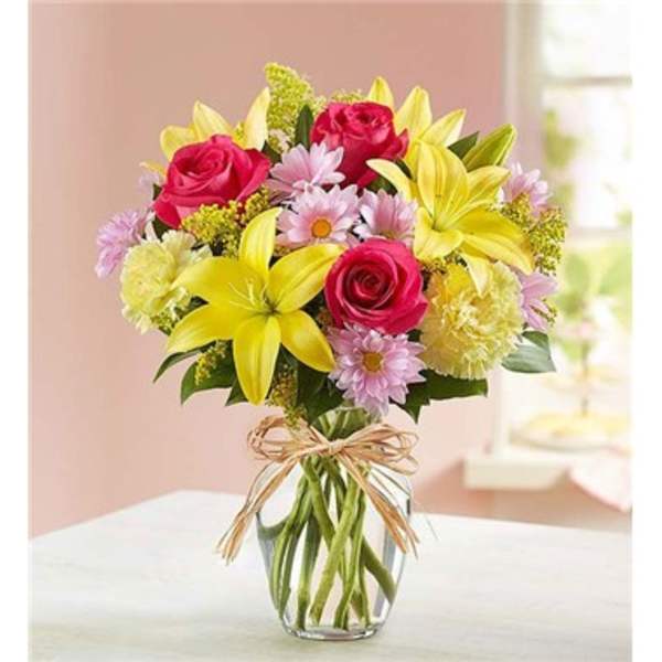Bouquet of pink roses and yellow lilies in a clear glass vase