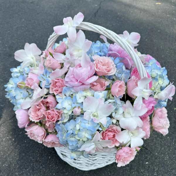 Basket of pink and blue flowers with a white handle