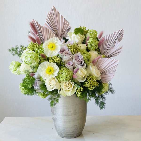 Bouquet of white and lavender roses with green blooms in a tall vase