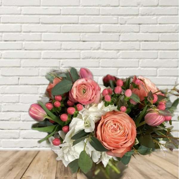 Bouquet of coral roses, pink tulips, and white hydrangeas in a vase