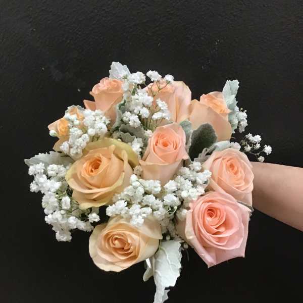 Handheld bouquet of peach roses and white baby's breath