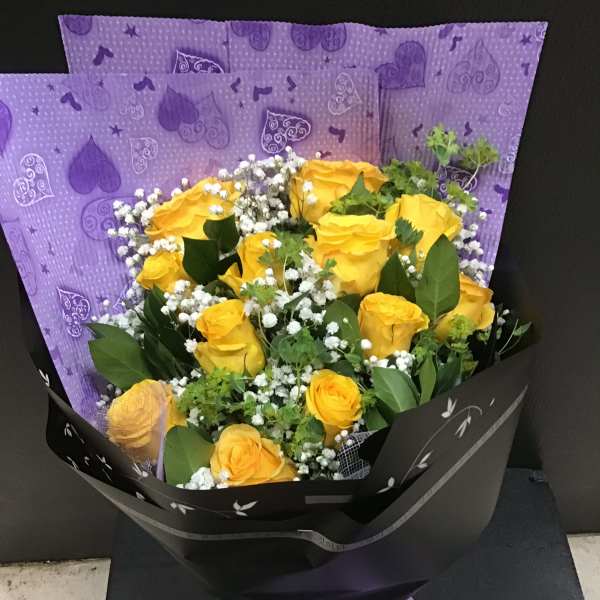 Bouquet of yellow roses with white baby's breath in black and purple wrapping