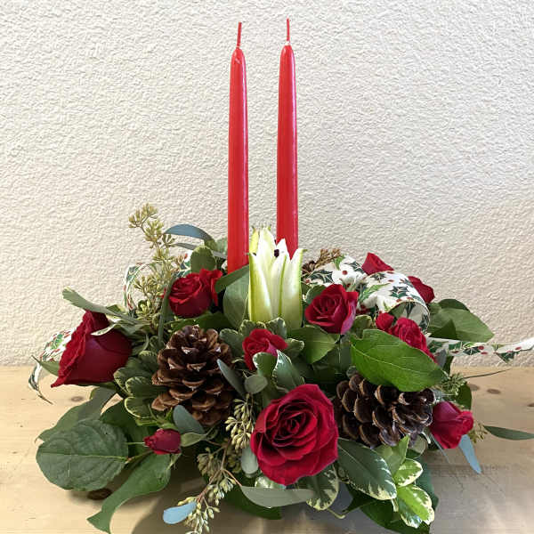 Red roses and pinecones arranged with two tall red candles.