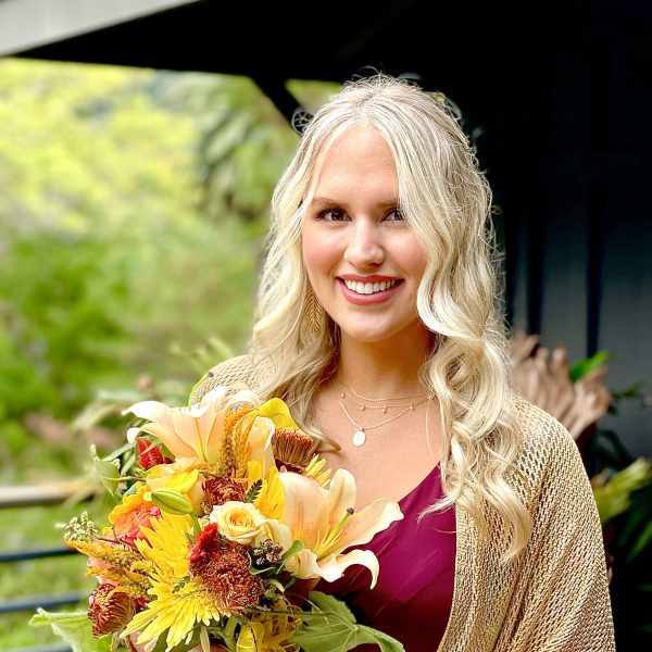 Woman holding a bouquet of yellow, orange, and white flowers