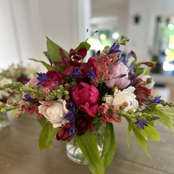 Mixed bouquet of pink, white, and purple flowers in a clear glass vase