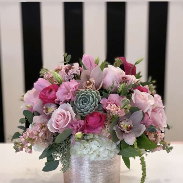 Pink floral arrangement in a silver vase with a succulent center